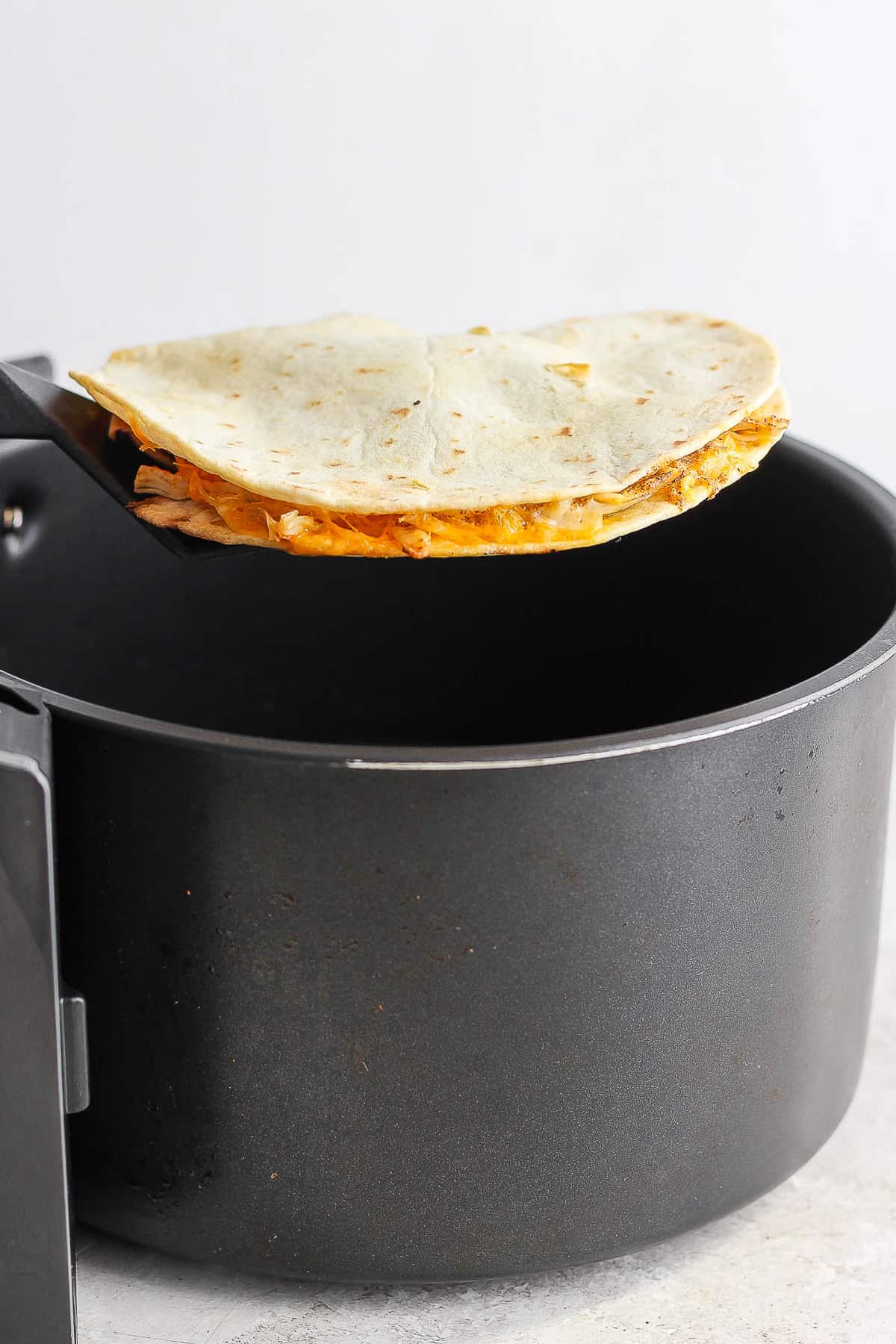 A quesadilla coming out of the air fryer.
