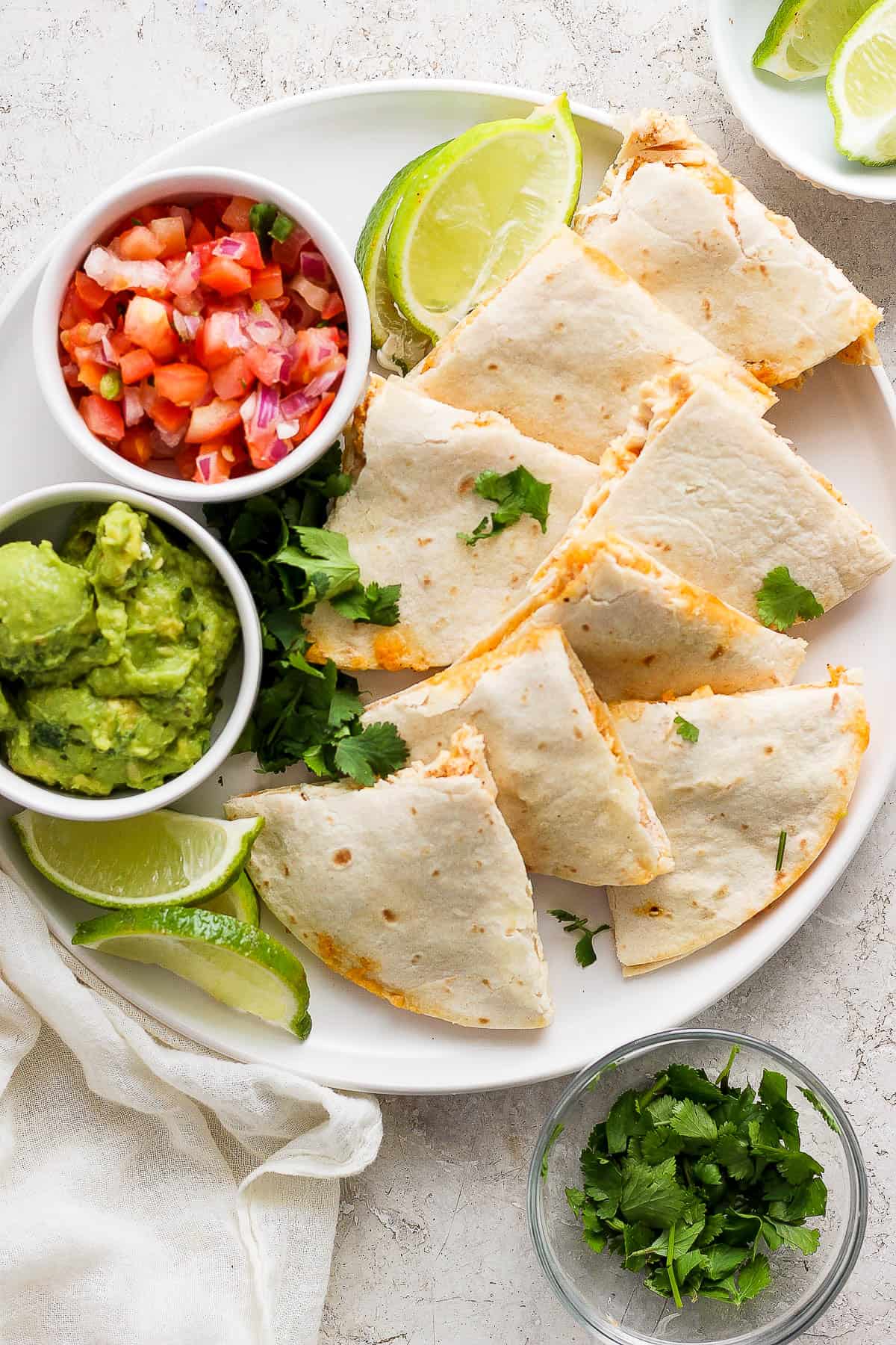 Air Fryer Chicken Quesadillas on a plate served with a side of guacamole and pico de gallo.