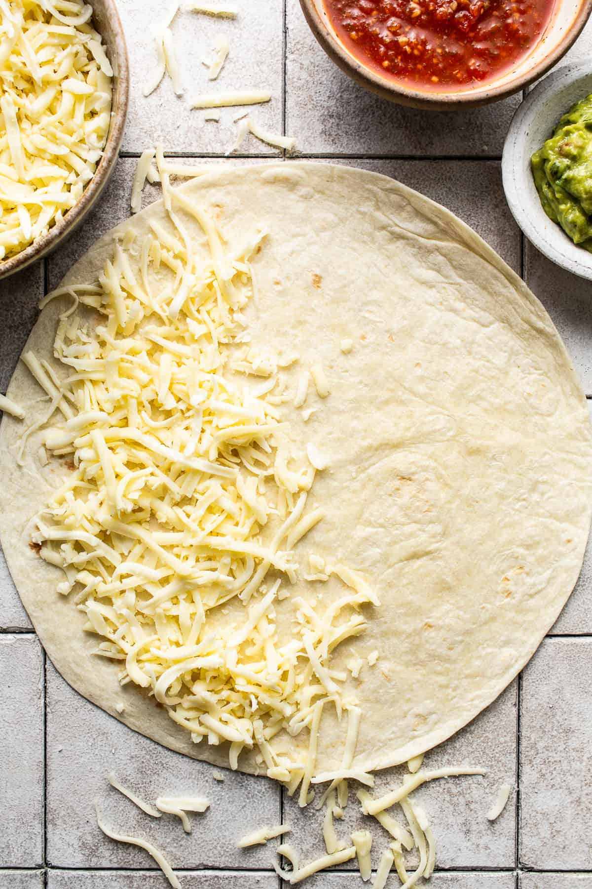 Shredded cheese on one half of a large flour tortilla to make quesadillas.