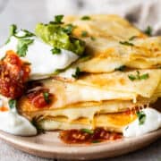 Cheese quesadillas on a plate stacked on top of each other.