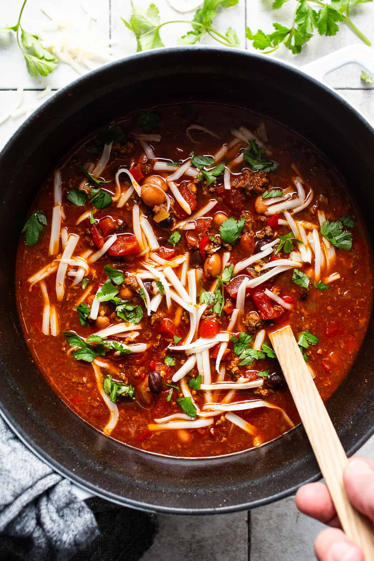 Chorizo chili in a pot with fresh cilantro and shredded cheese ready to be served.