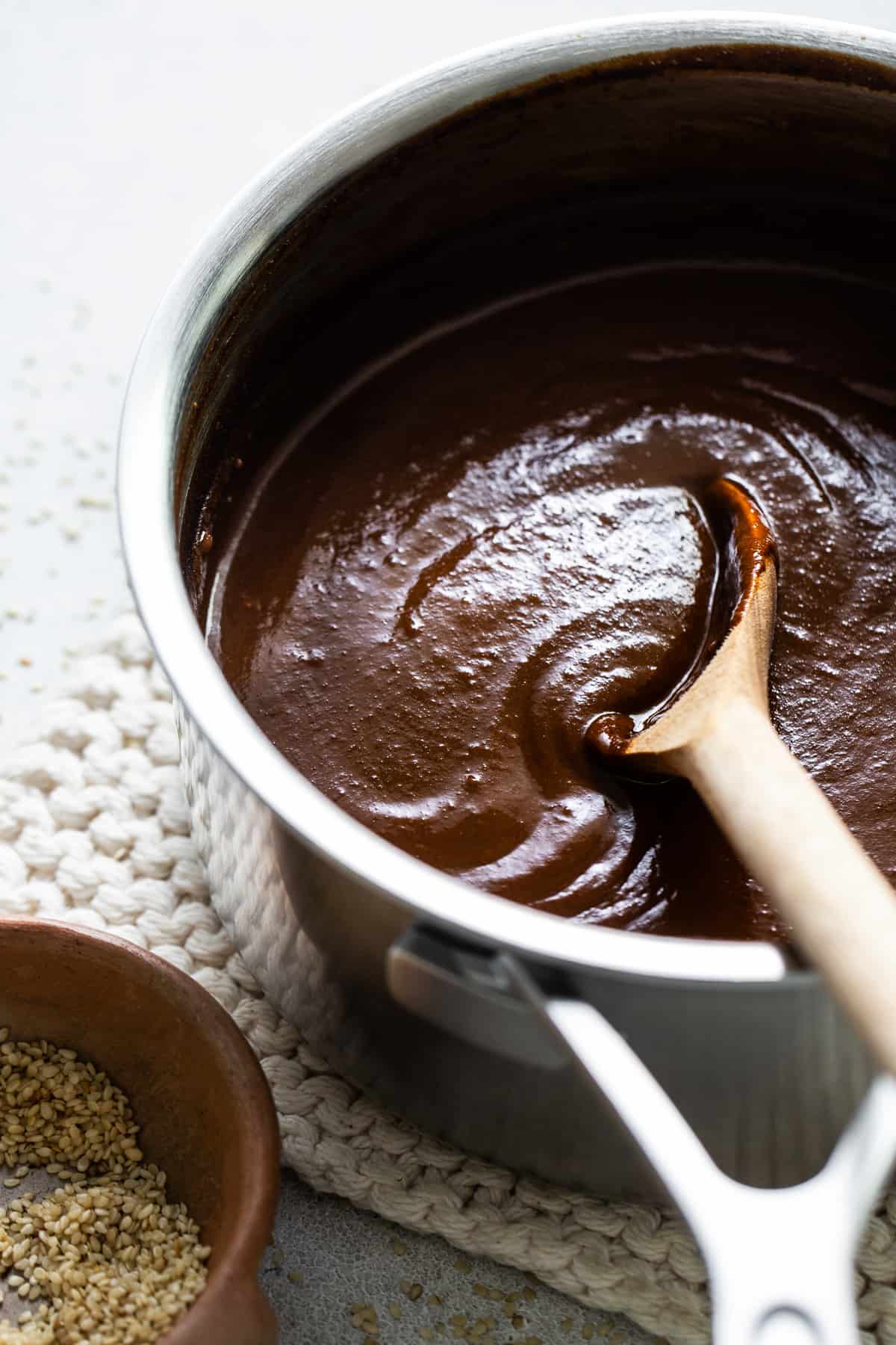 Mole sauce in a sauce pan with a wooden spoon.