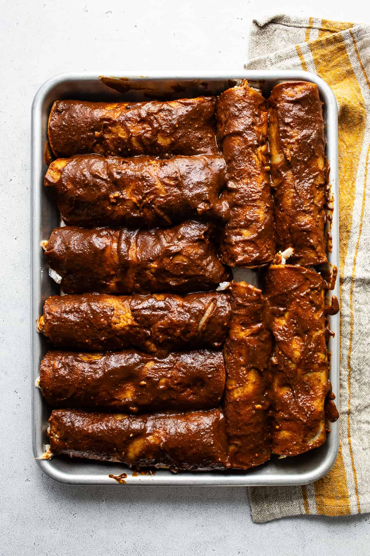 Filled and rolled enmoladas on a baking sheet ready to serve.