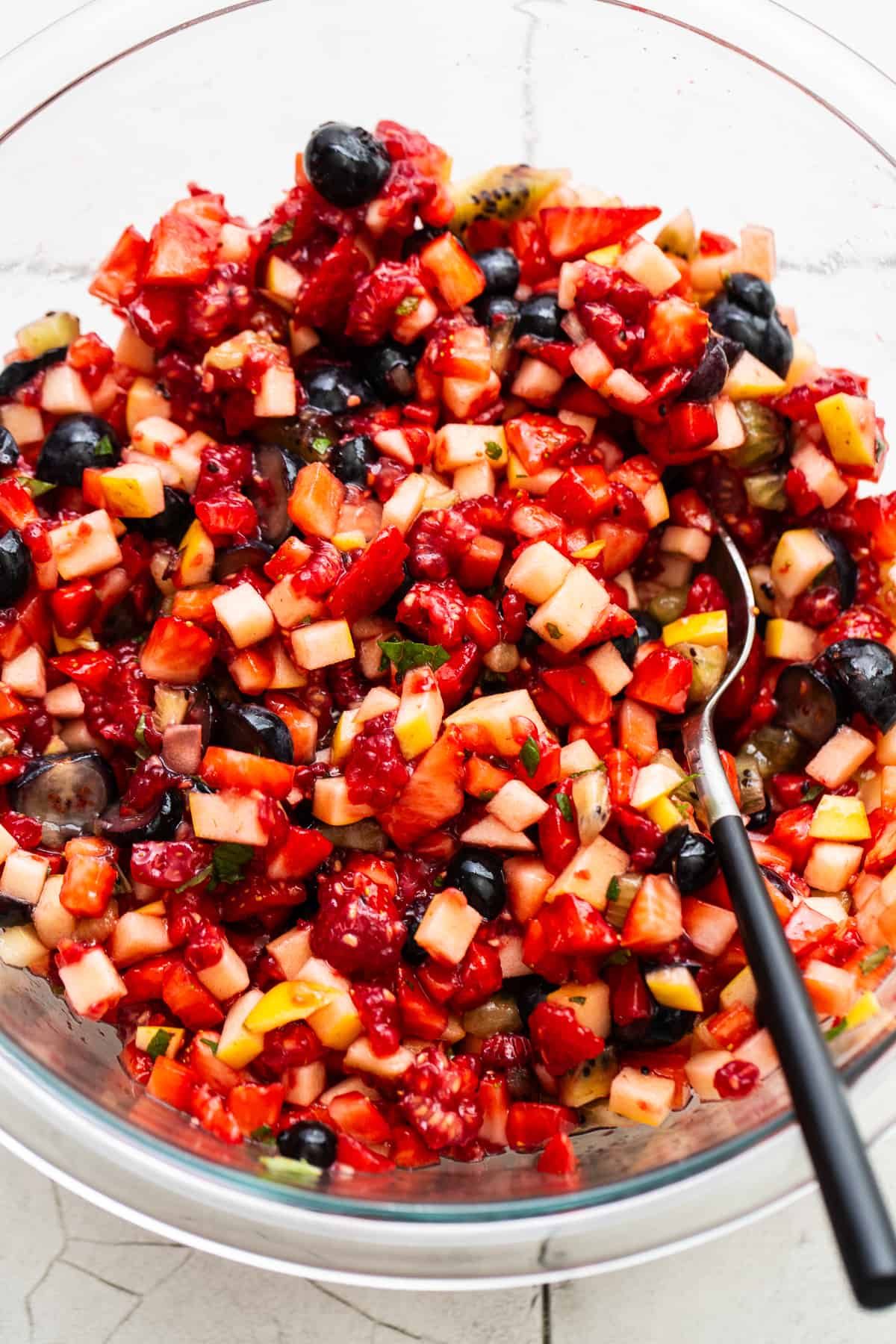 Finely diced fruit salsa in a mixing bowl with a serving spoon.