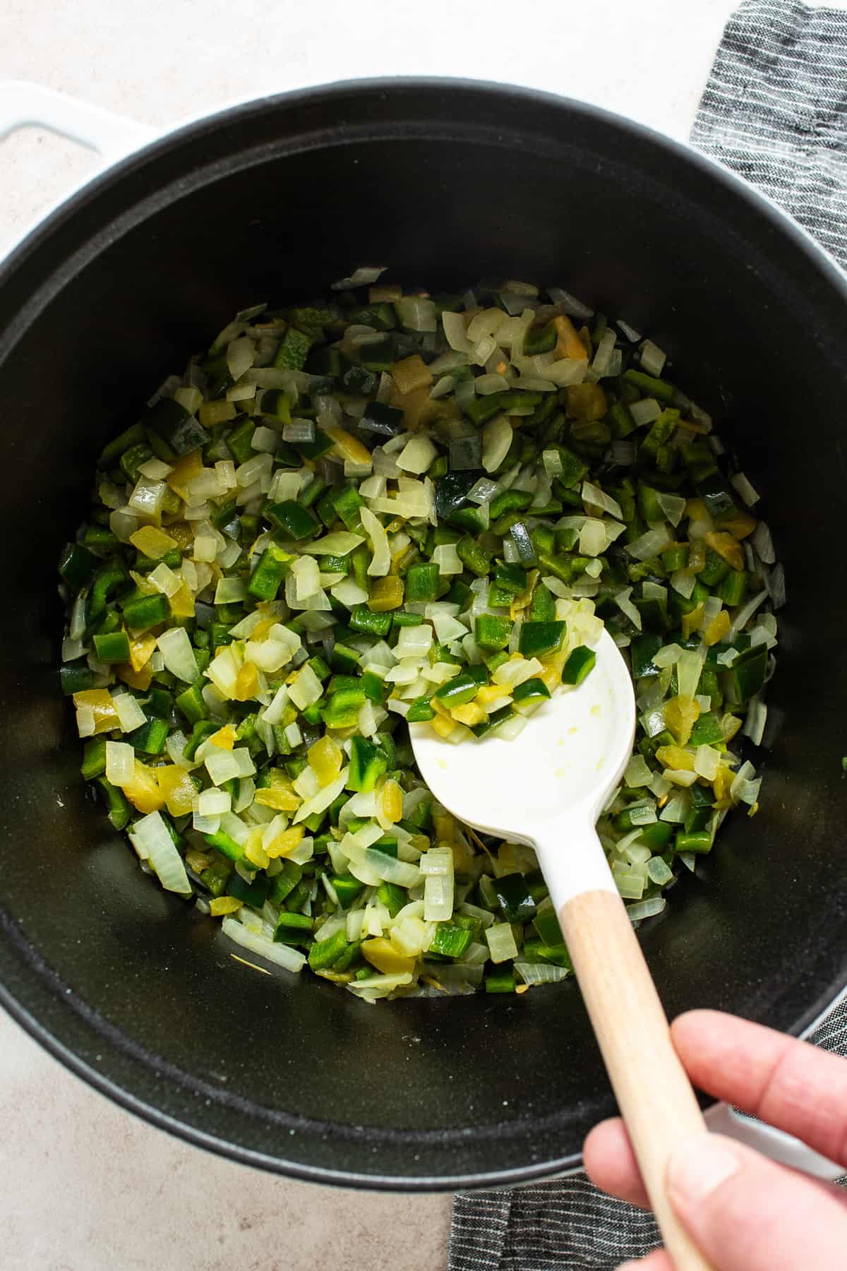 Onions and green peppers cooking in a large Dutch oven.