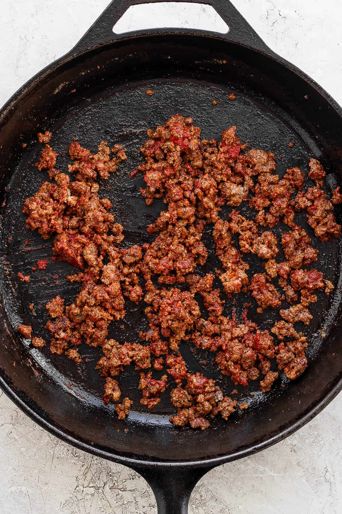 Taco meat being cooked in a cast iron skillet.