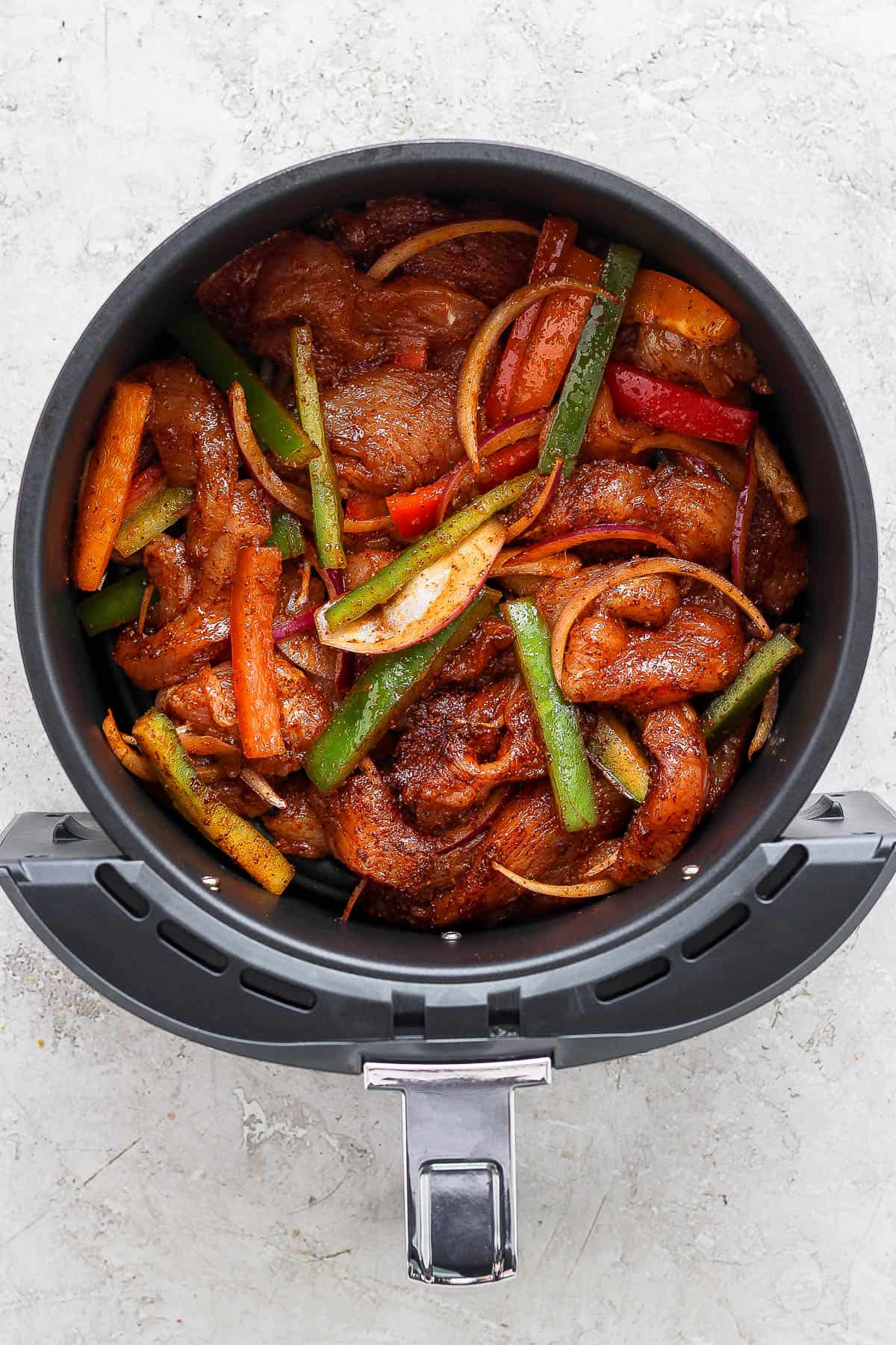 Raw chicken and fajita vegetables in the air fryer bowl 