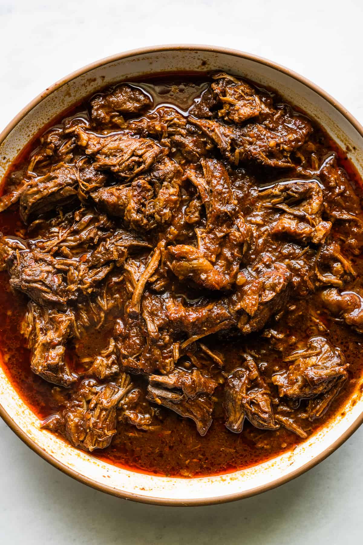 A bowl of birria on a table for making birria tacos.