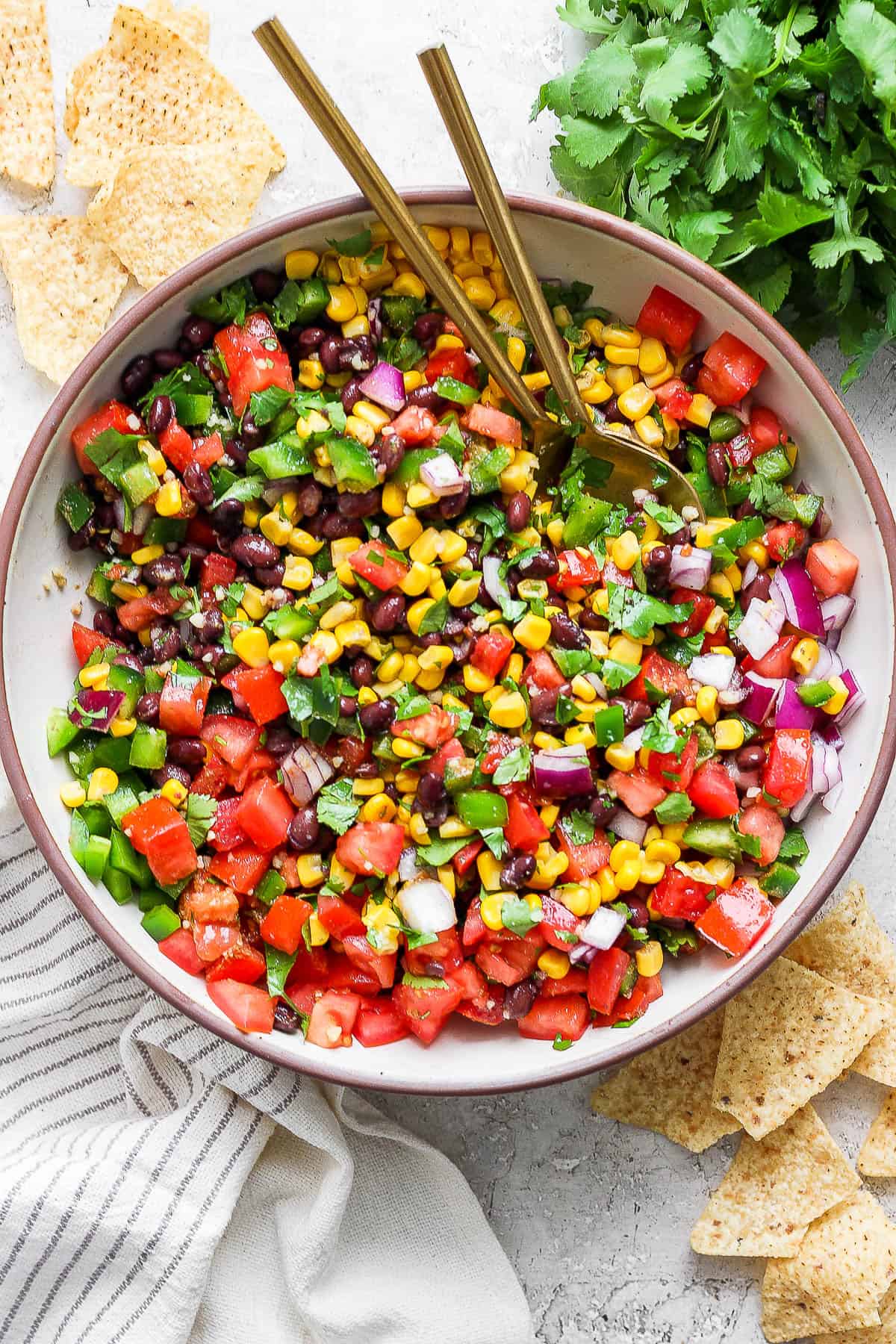 A serving bowl of black bean and corn salsa with tortilla chips on the side.