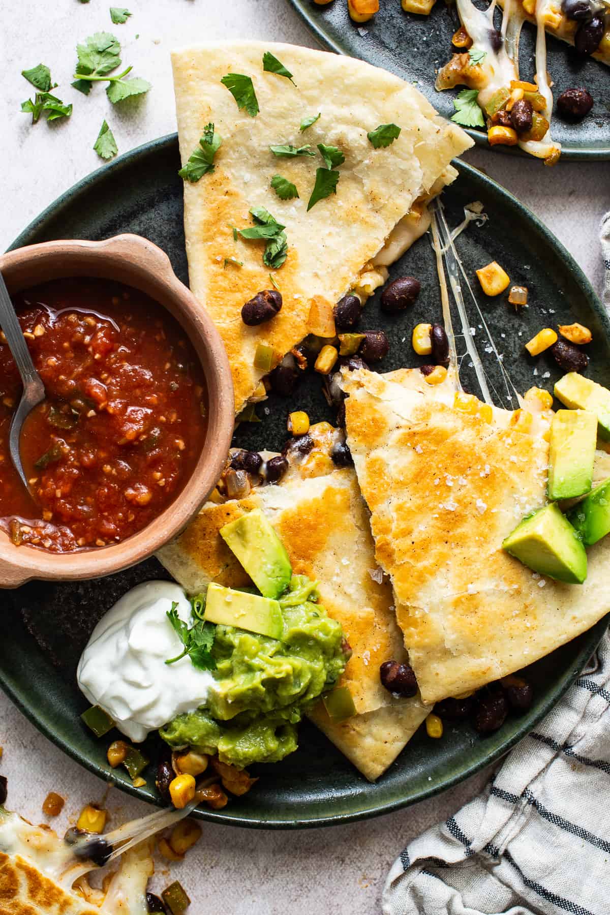 A crispy golden brown black bean quesadilla on a plate sliced into triangles with cheese oozing out.