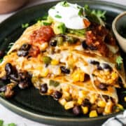 Black bean quesadillas on a plate with sour cream, guacamole, and salsa.