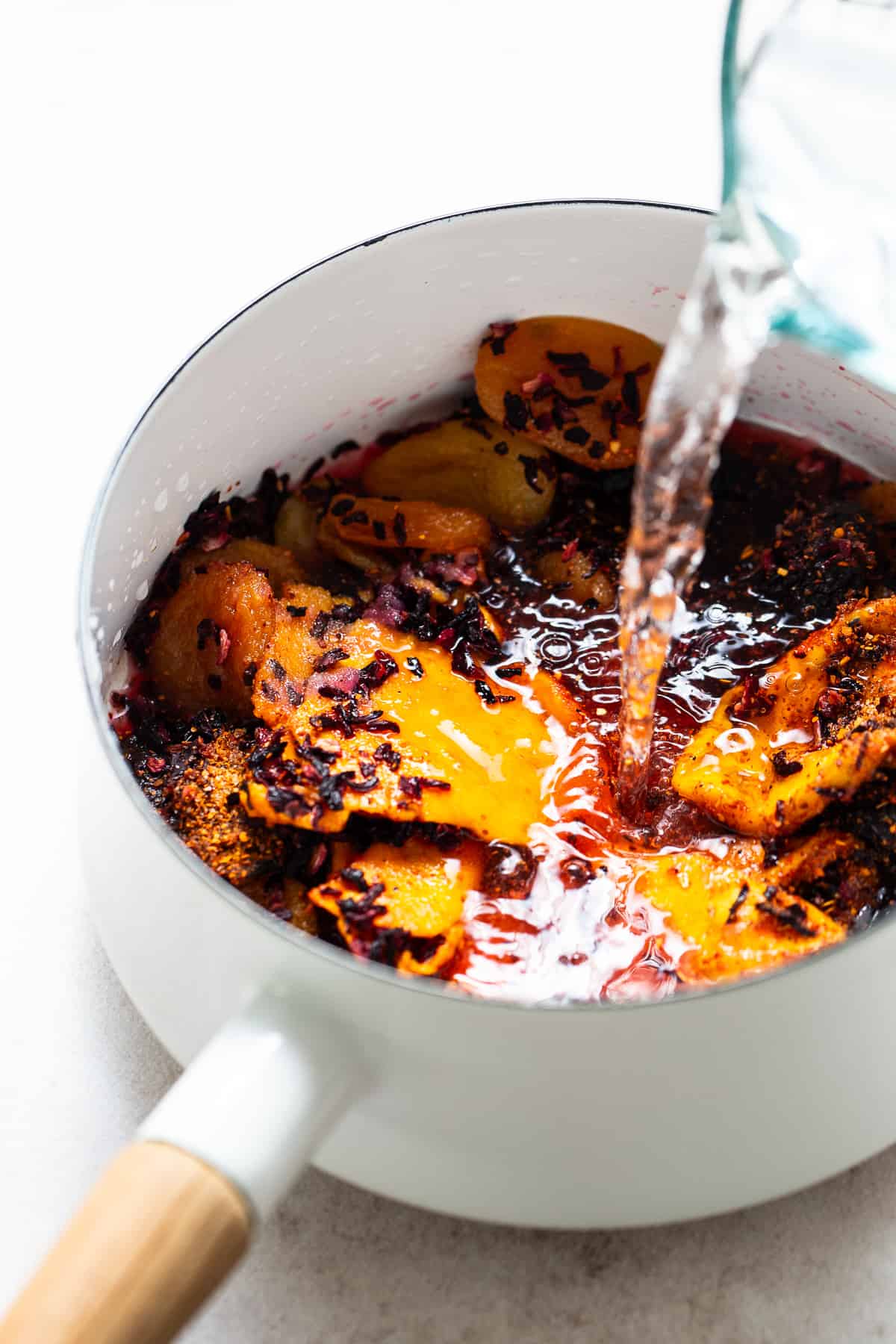 Water being poured into a pot of ingredients to make homemade chamoy.