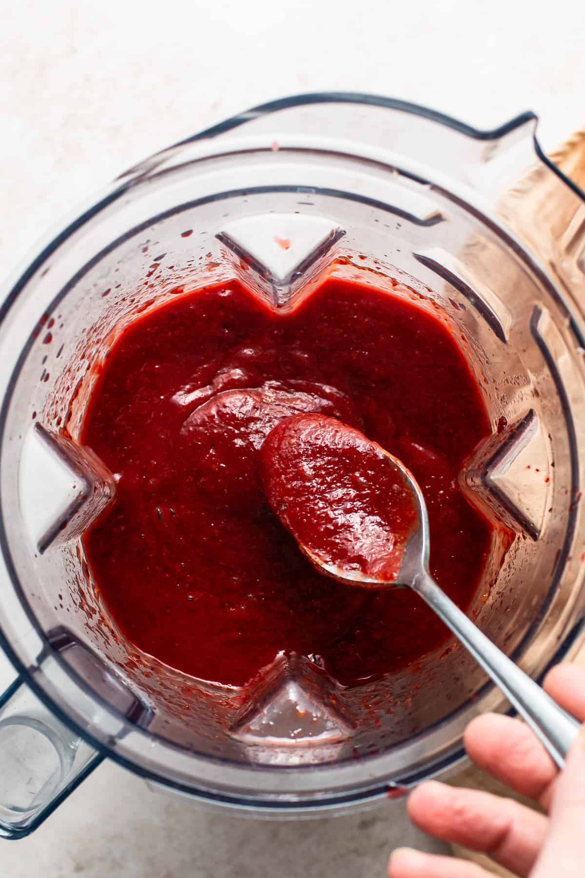 A spoon being dipped in chamoy in a blender.
