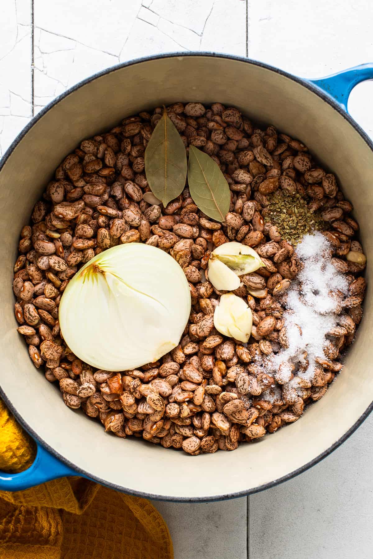 Dried pinto beans in a pot with bay leaves, onion, salt, Mexican oregano and garlic to make charro beans.