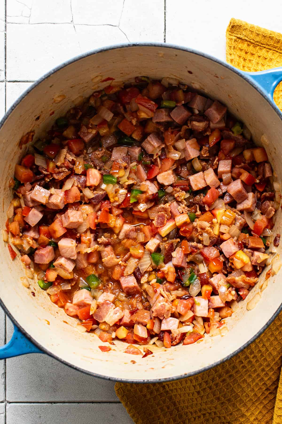 Bacon, ham, tomatoes, jalapeño, and more cooking in a pot to make charro beans.