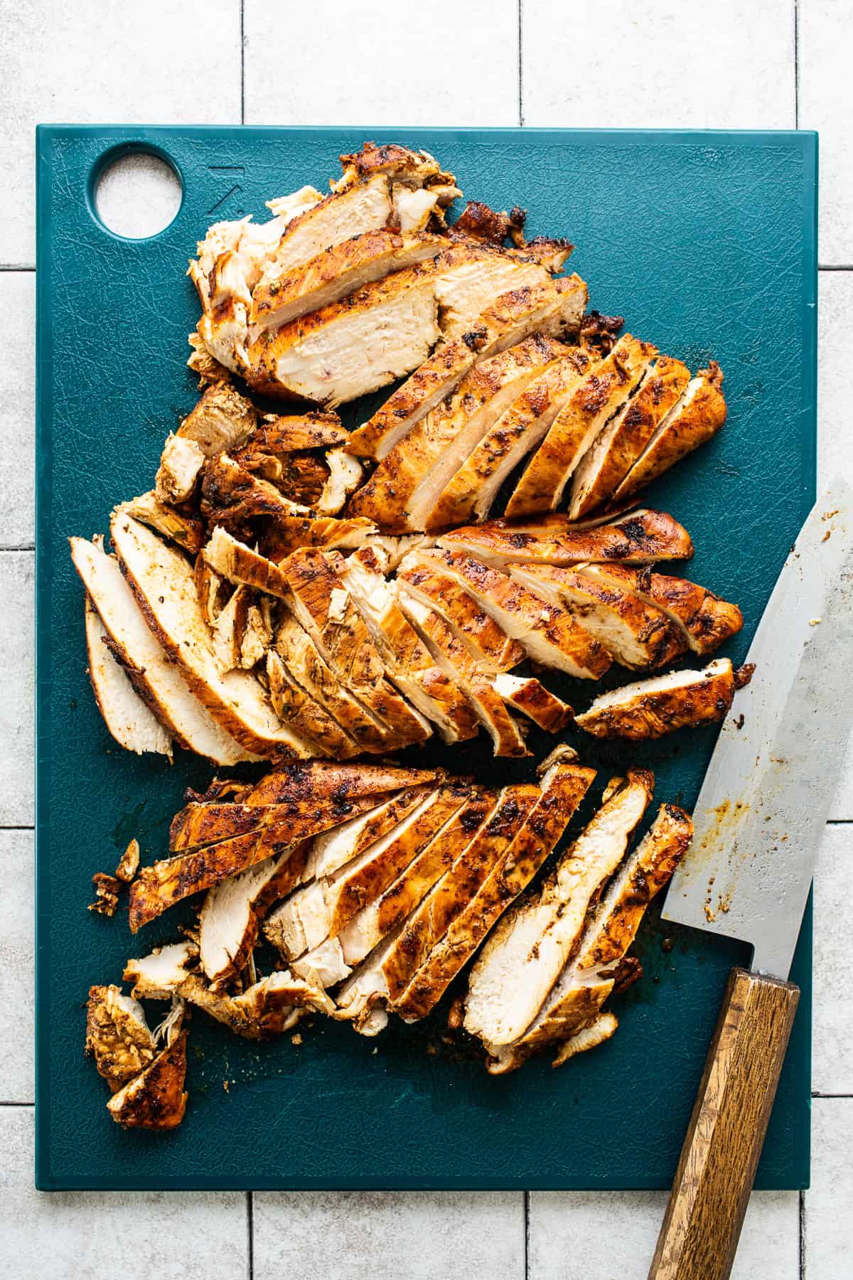 Cooked fajita chicken cut into strips on a cutting board.