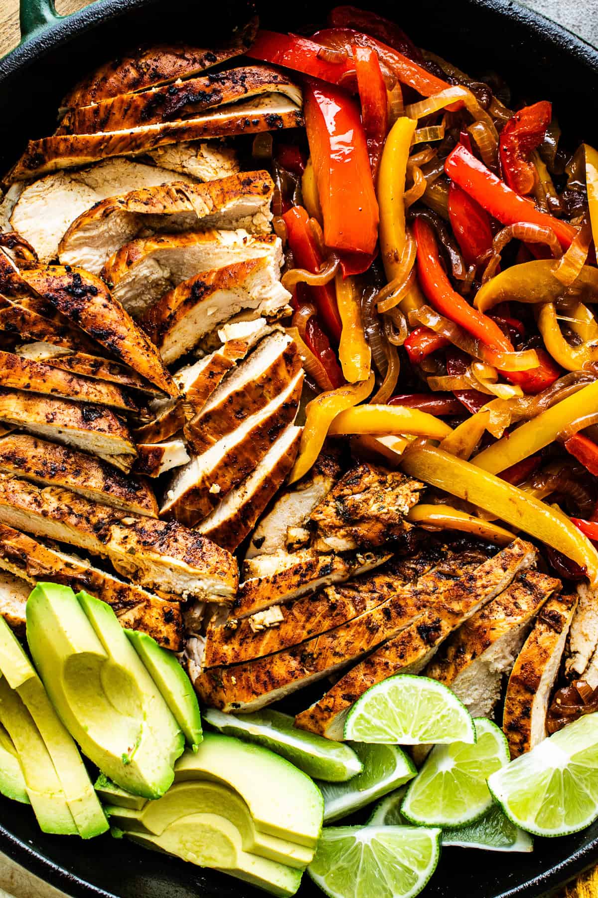 Sliced chicken fajitas, peppers, and onions in a large skillet ready to serve. 