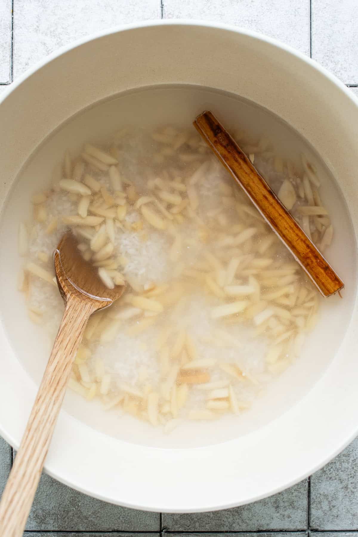 Rice, almonds, cinnamon, and water all soaking in a large bowl.