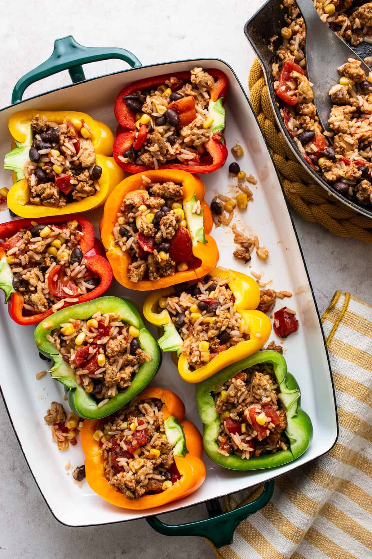 Mexican stuffed peppers on a baking dish with filling inside before being baked in the oven.