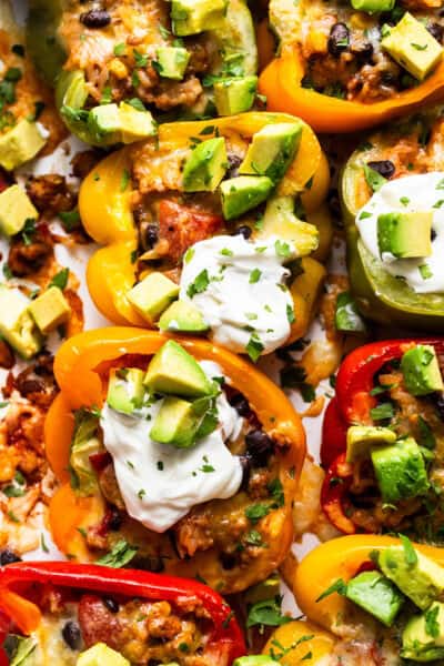 Mexican stuffed peppers served with a dollop of sour cream, avocado, and cilantro.
