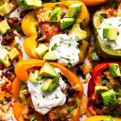 Mexican stuffed peppers served with a dollop of sour cream, avocado, and cilantro.