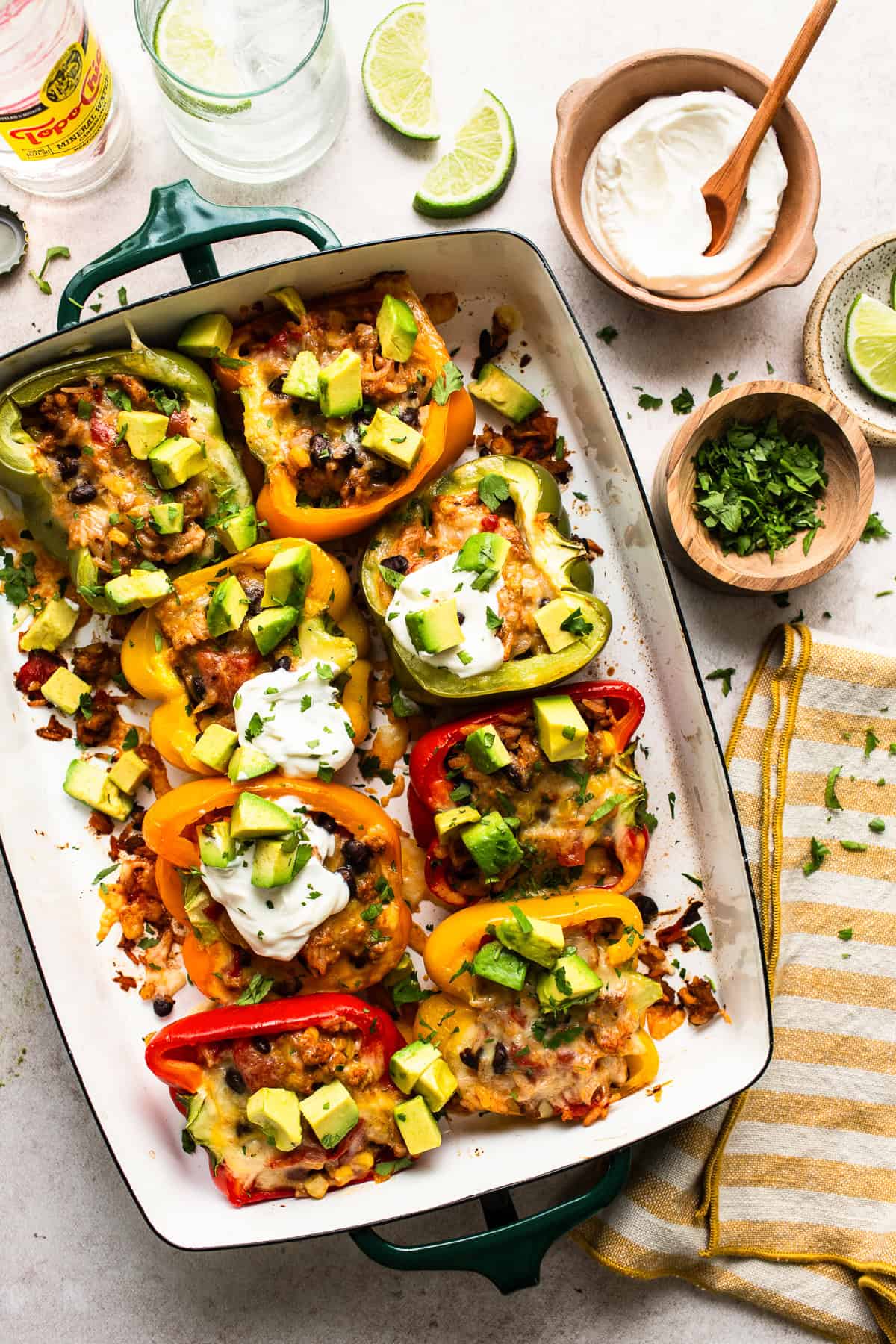 Mexican Stuffed Peppers fresh out of the oven served with sour cream, avocado, and cilantro.
