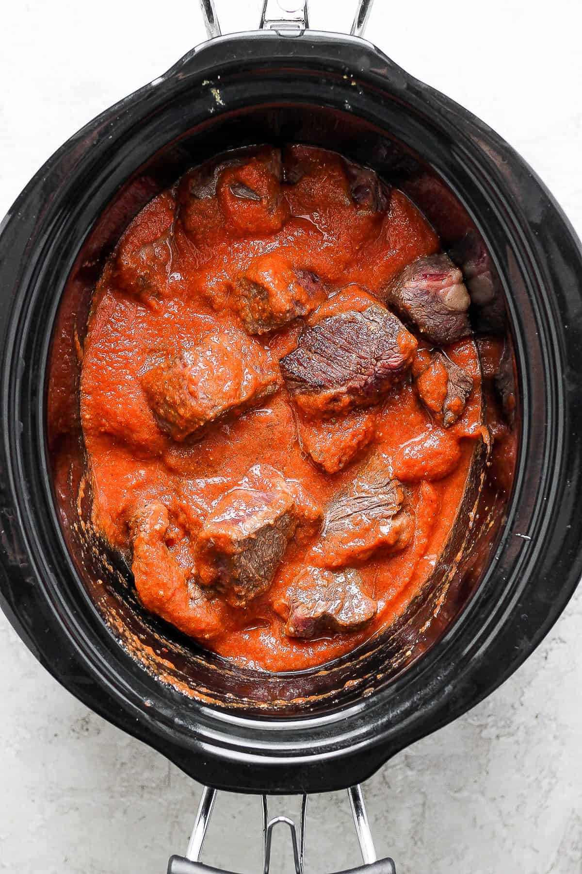 Tinga sauce poured into the crockpot with cooked meat