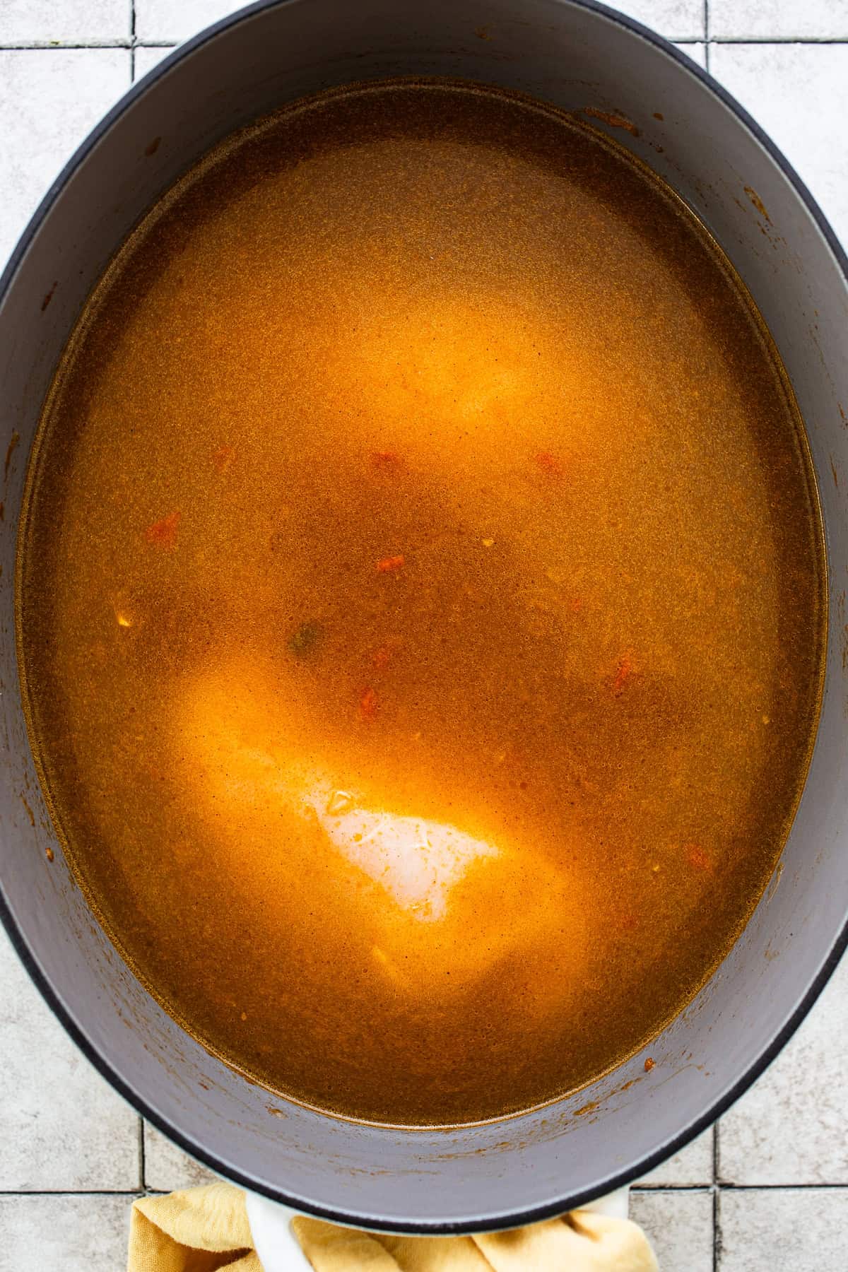 Chicken broth and chicken in a pot of sopa de lima before being cooked.