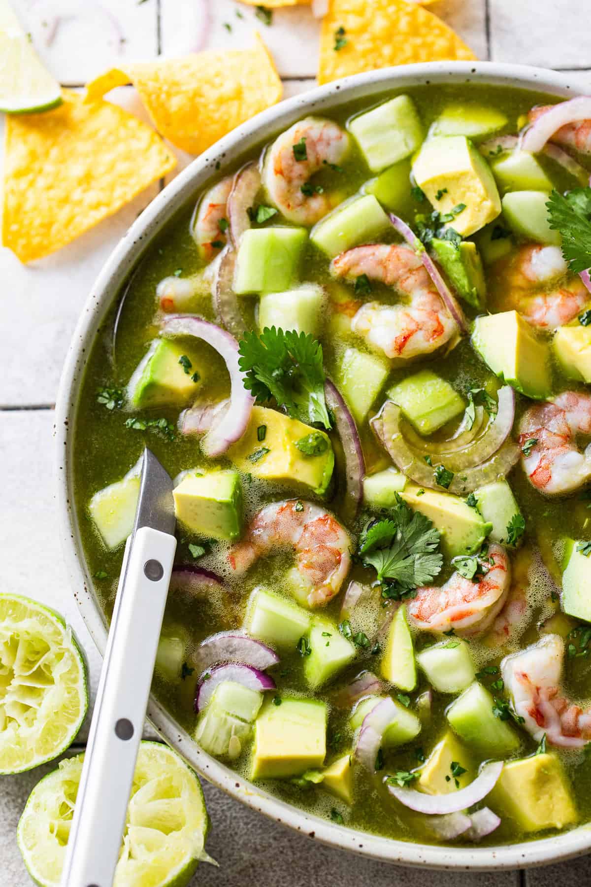Aguachile in a bowl with avocado, cilantro, cucumber, and red onion.