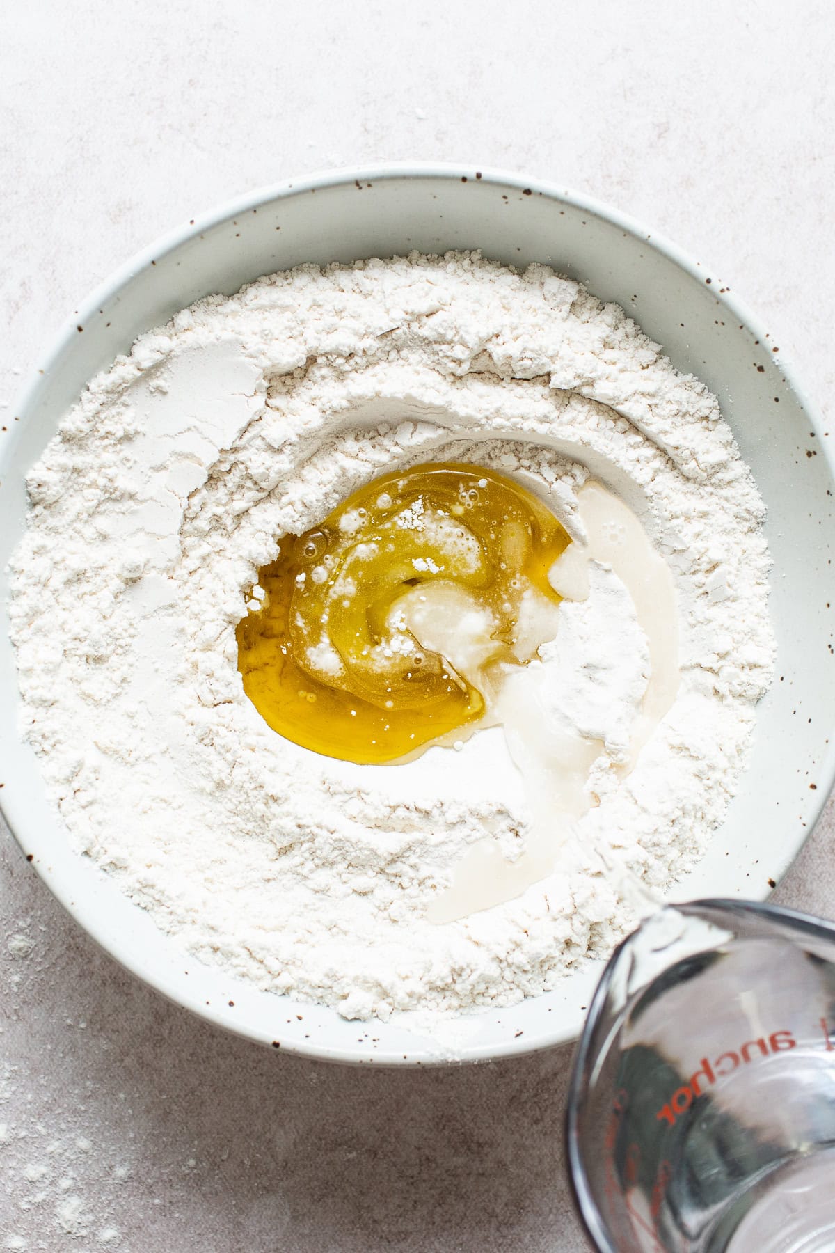 Flour, oil, water, and baking powder in a bowl to make flour tortillas.
