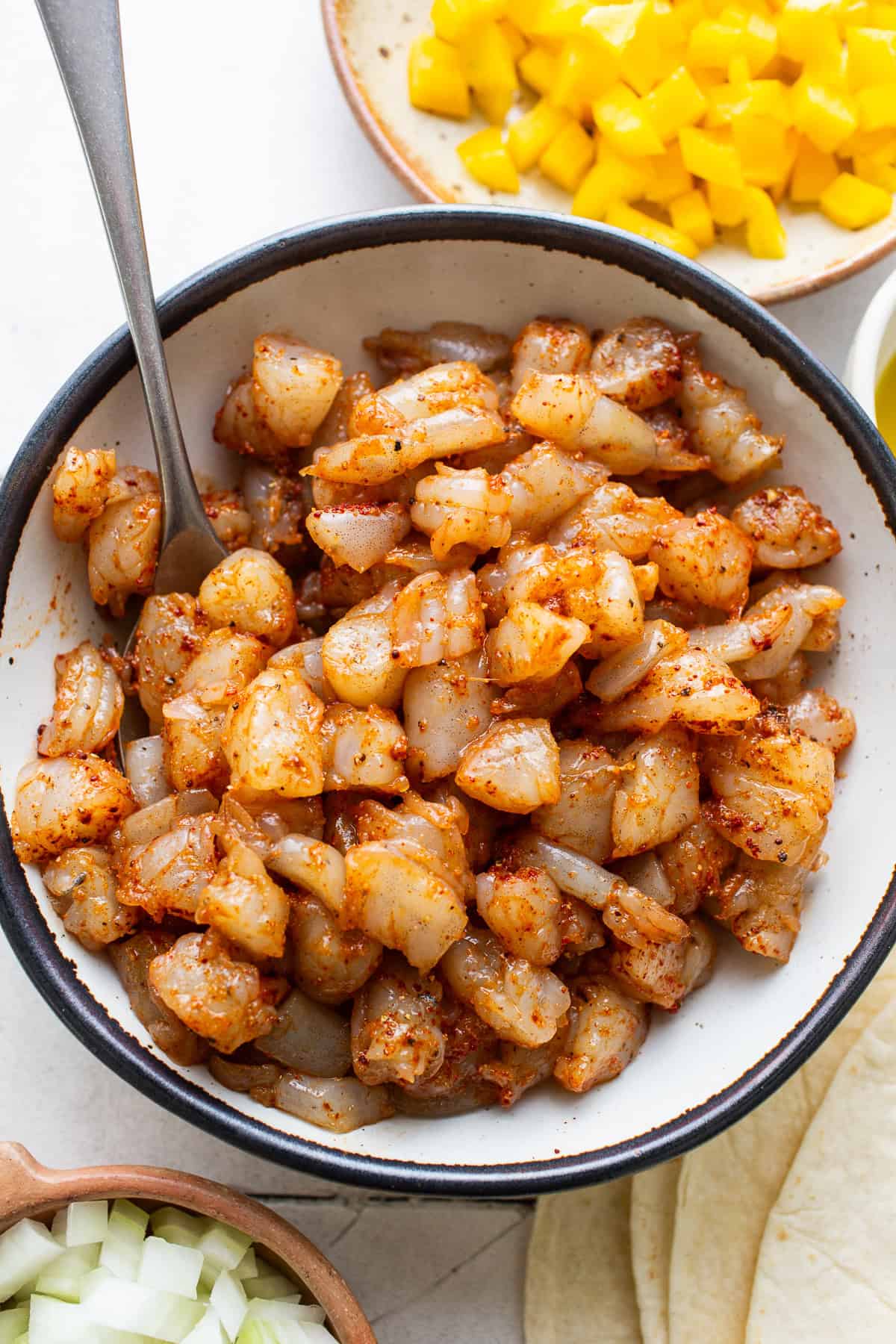 Seasoned shrimp for shrimp quesadillas tossed in a bowl.