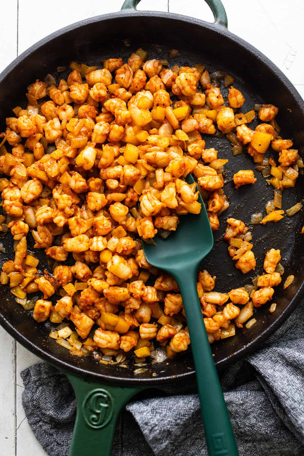 Cooked shrimp, onions, and bell peppers in a skillet.