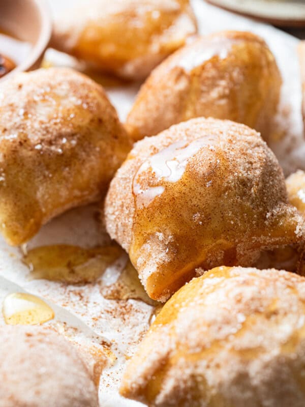 Sopapillas on a plate covered with cinnamon sugar and drizzled with honey.