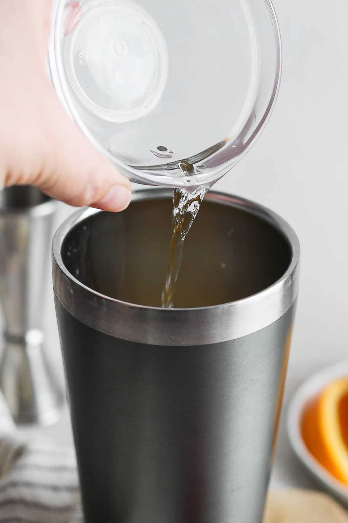 Tequila being poured into a cocktail shaker.