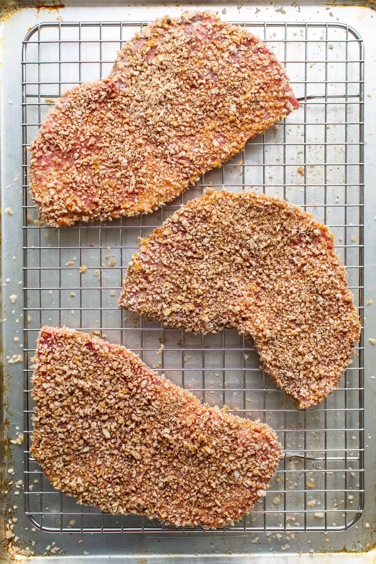Breaded torta de milanesa before being fried on a sheet pan