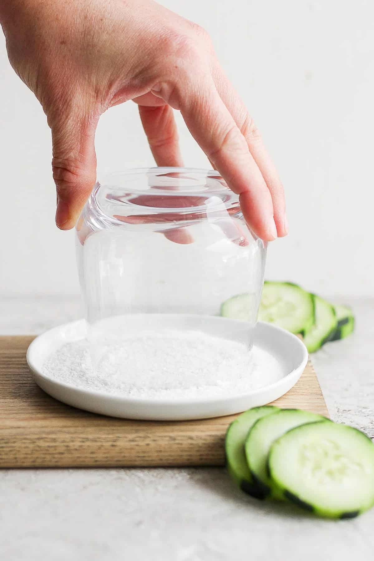 A glass being dipped in flaky sea salt.