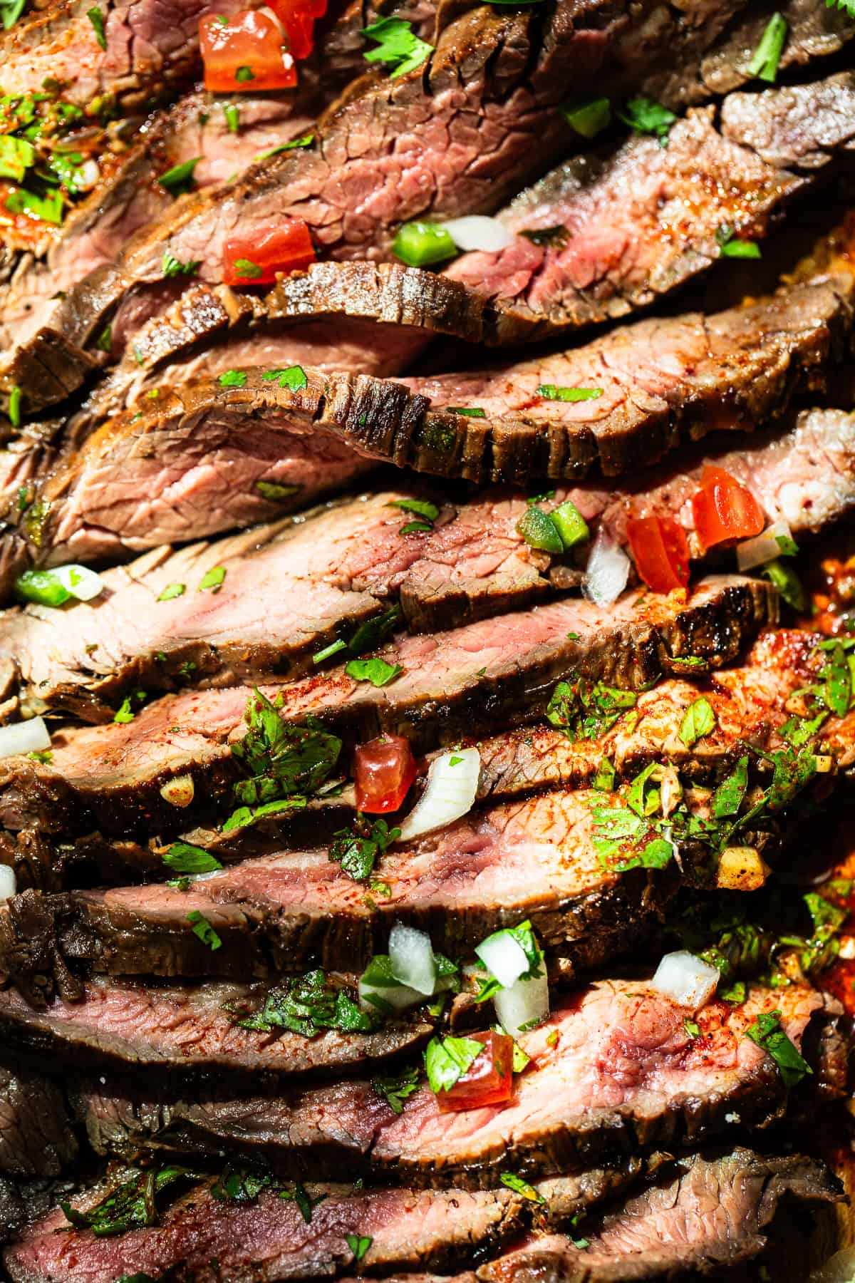 A very close up shot of thinly sliced carne asada with the meat juices running out of it.