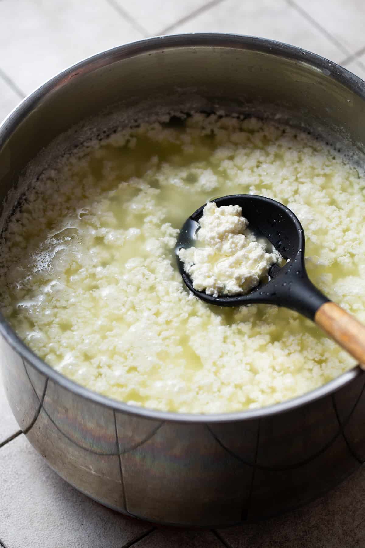 Heated milk and vinegar inside a large pot starting to curdle to make queso fresco.