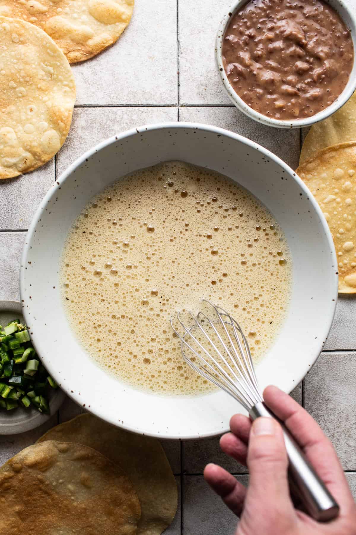 A large mixing bowl with all the eggs and seasonings being mixed until well combined. 