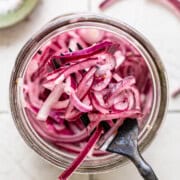 Mexican pickled onions in a glass jar on a fork ready to be eaten.
