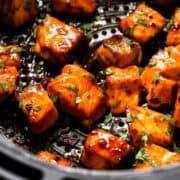Air fryer salmon bites in an air fryer basket tossed in a chipotle honey sauce.