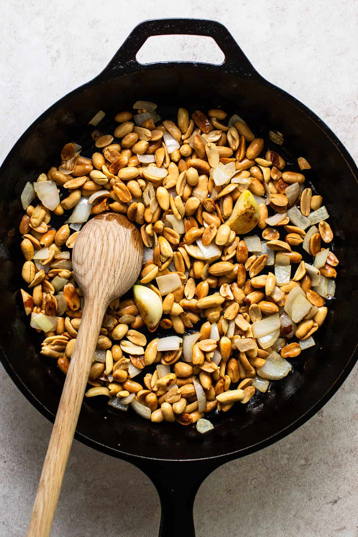 Peanuts, onions, and garlic pan frying in a skillet.