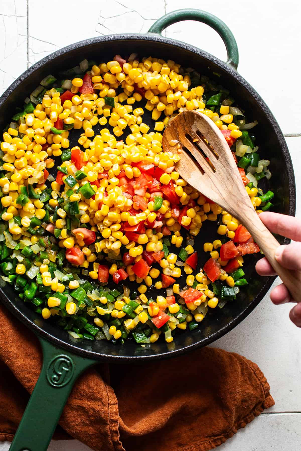 Corn, tomatoes, and peppers cooking in a skillet.
