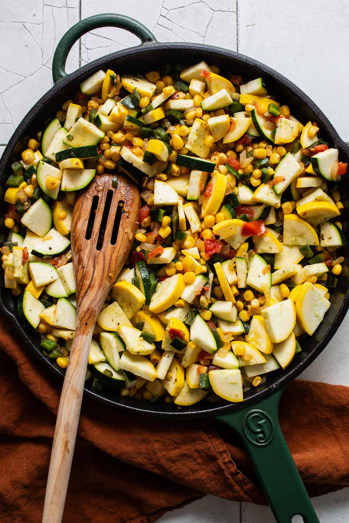 Zucchini and squash added to a skillet of vegetables for calabacitas.