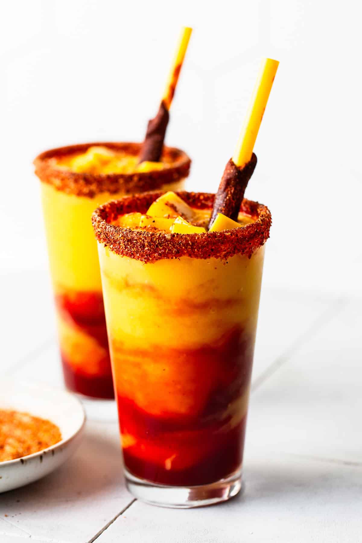 In a tall glass pour the mangonada mixture and add a tamarind candy straw.