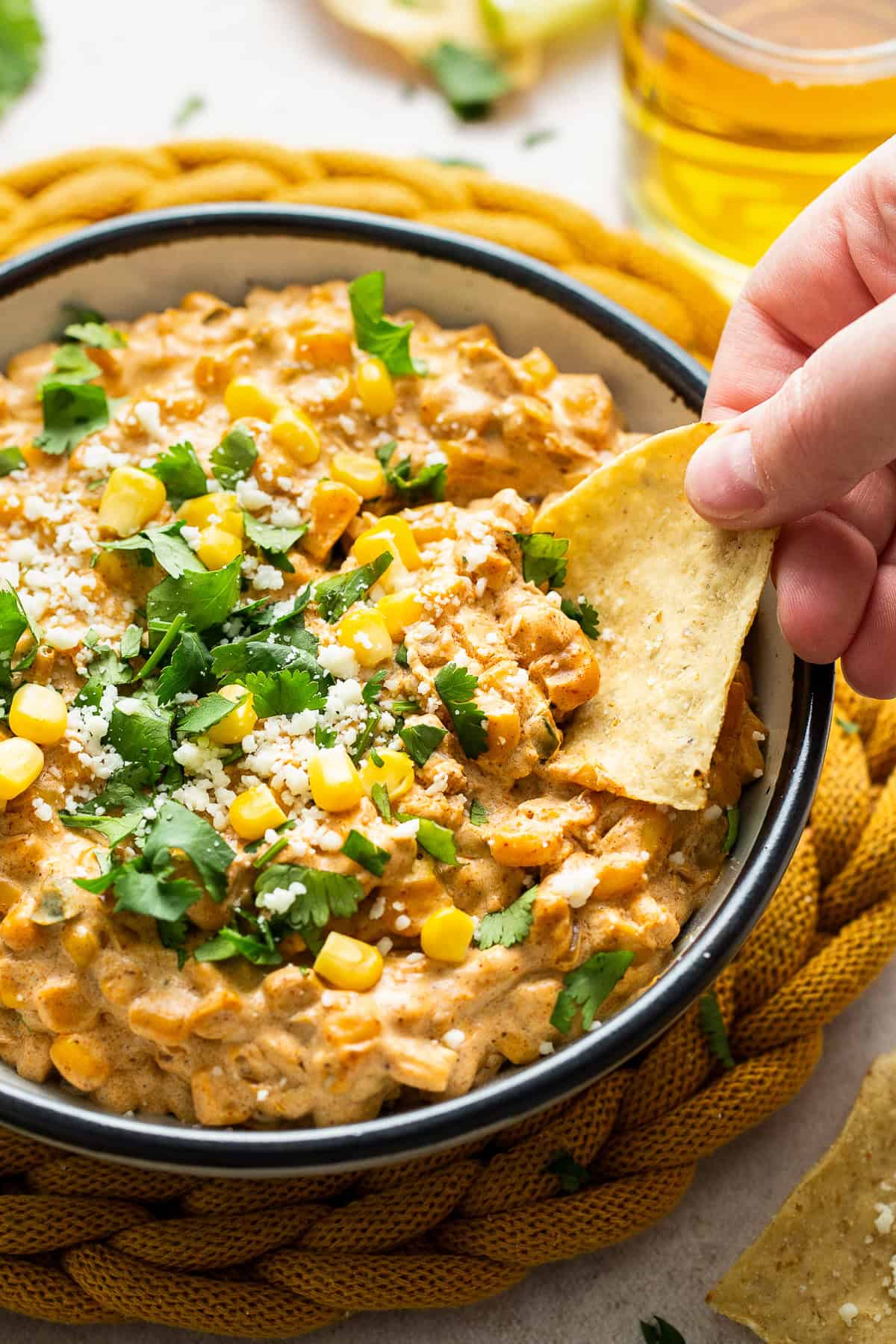 A chip being dipped into a bowl of street corn dip.