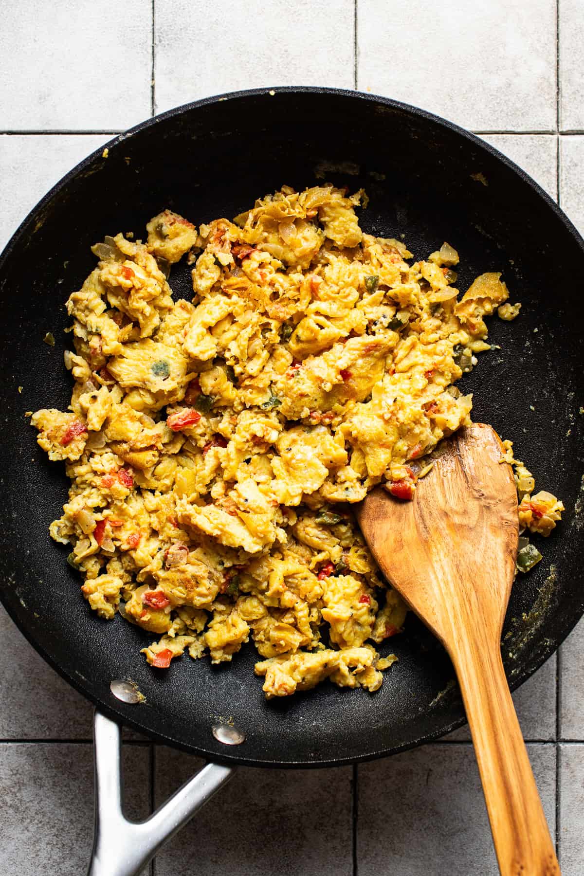 Cooked scrambled eggs in a skillet with peppers and onions.