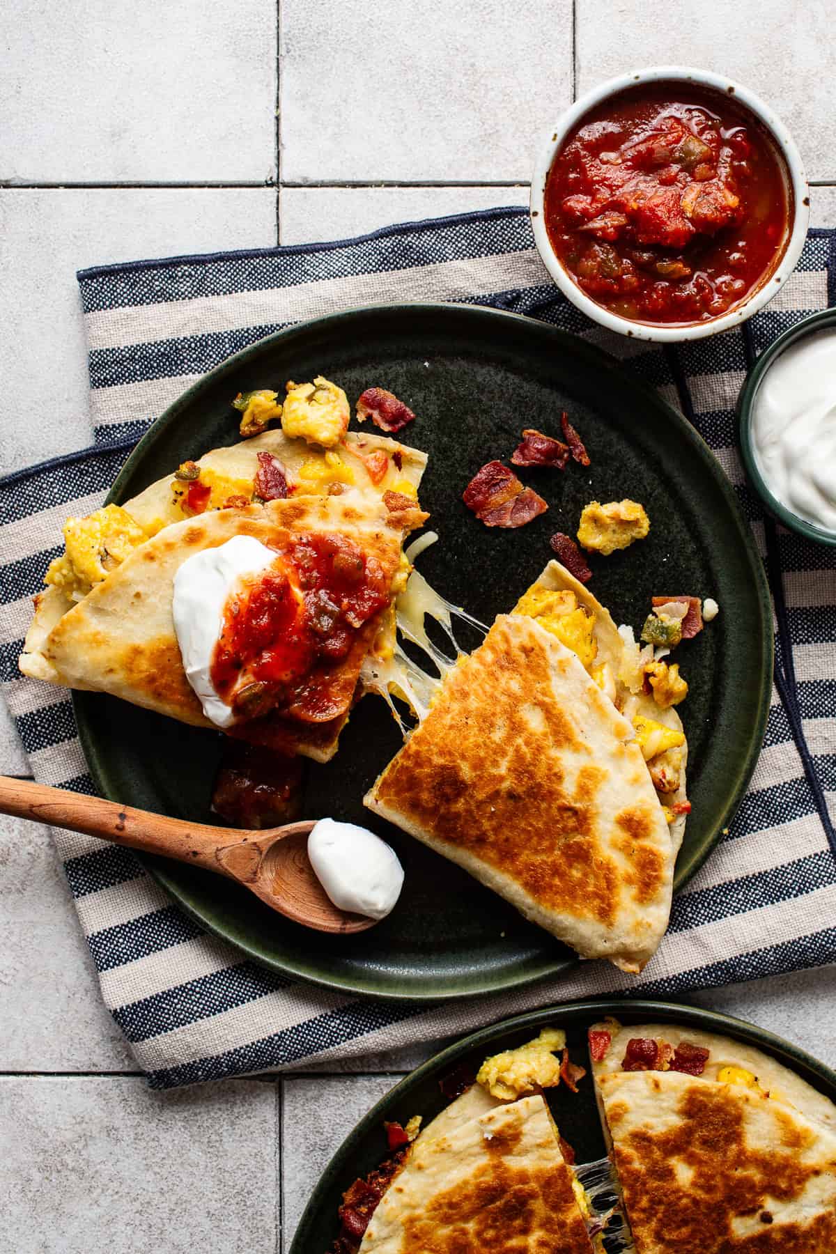 A breakfast quesadilla sliced in half and showing a cheese pull.