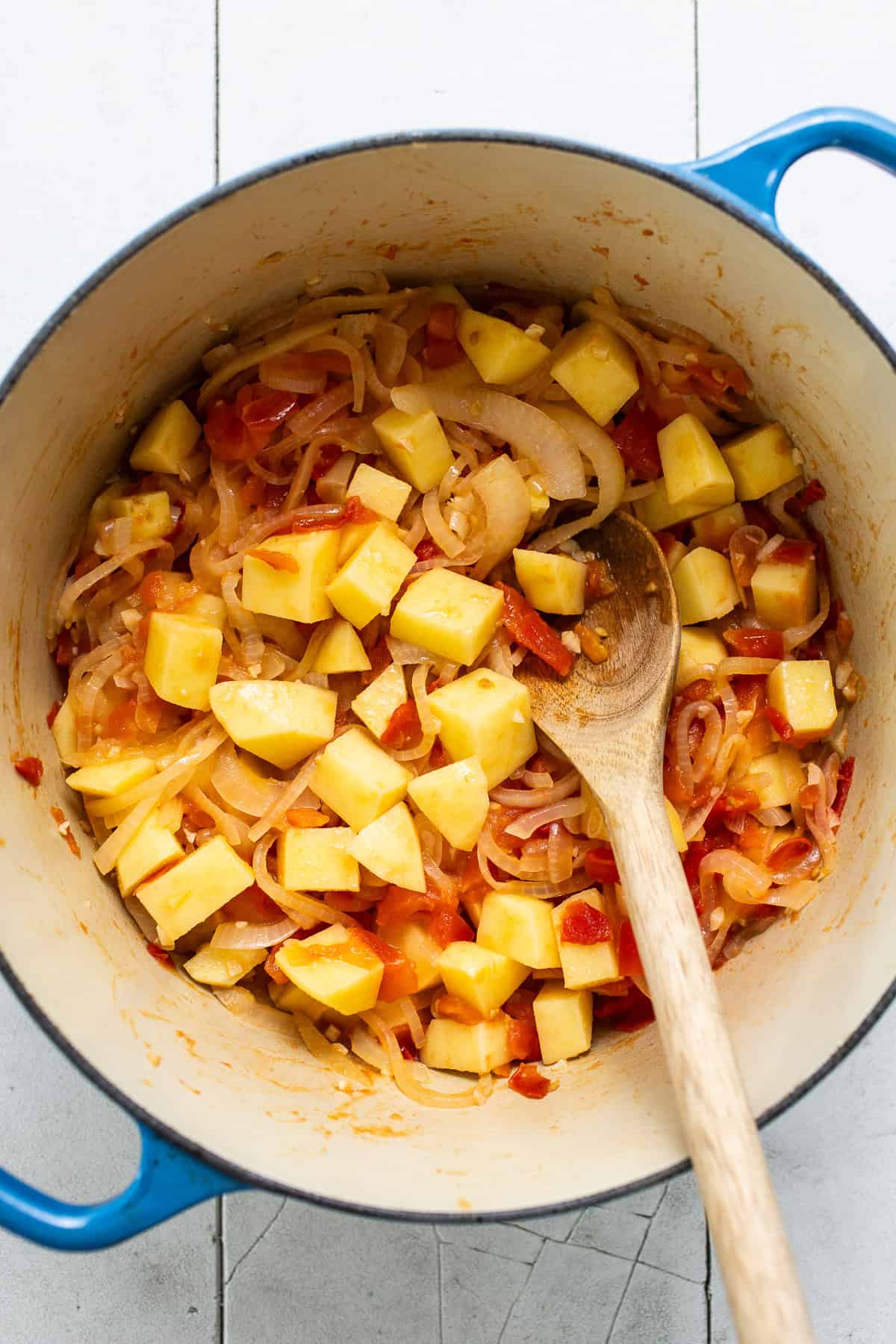 Diced potatoes, onions, tomatoes, and garlic in a pot to make caldo de queso.