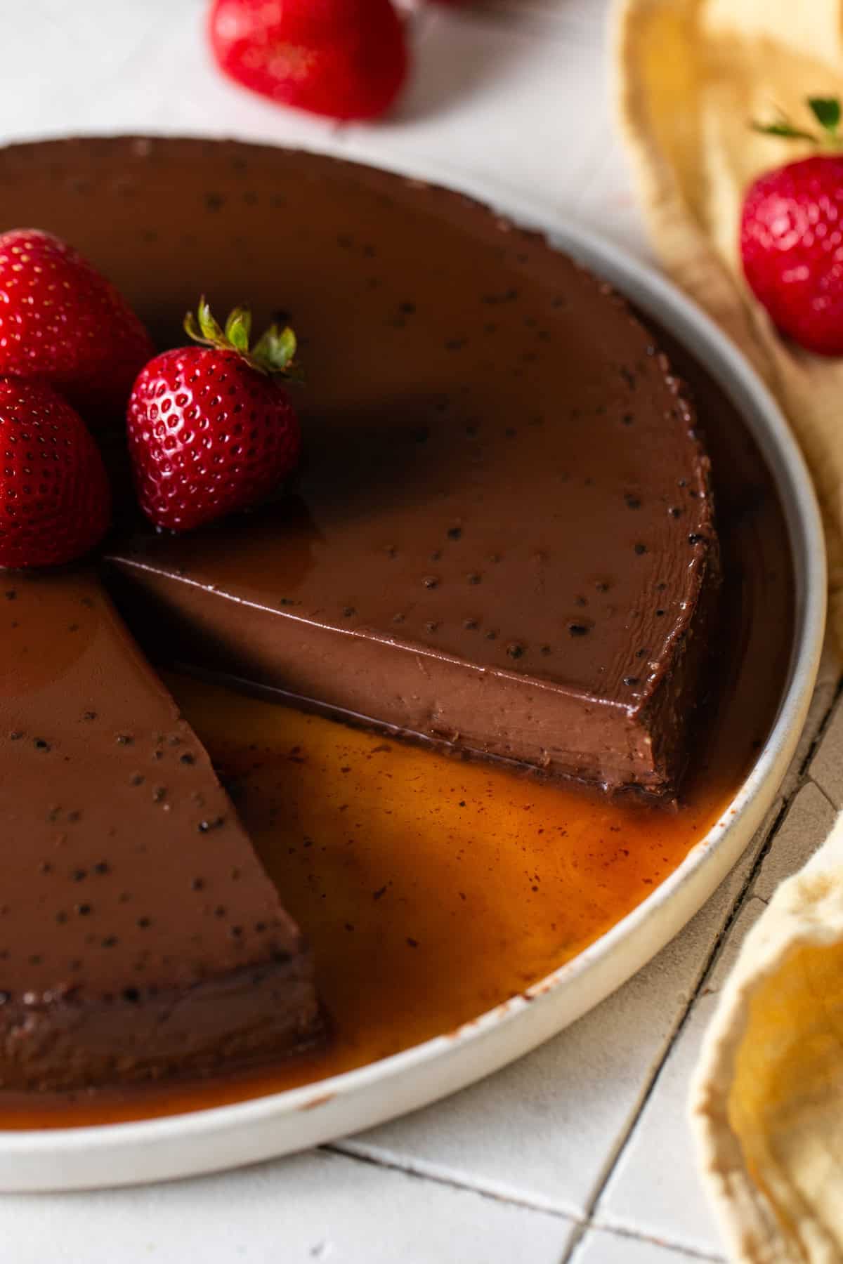Chocolate flan on a serving plate with a slice taken out revealing a creamy interior.